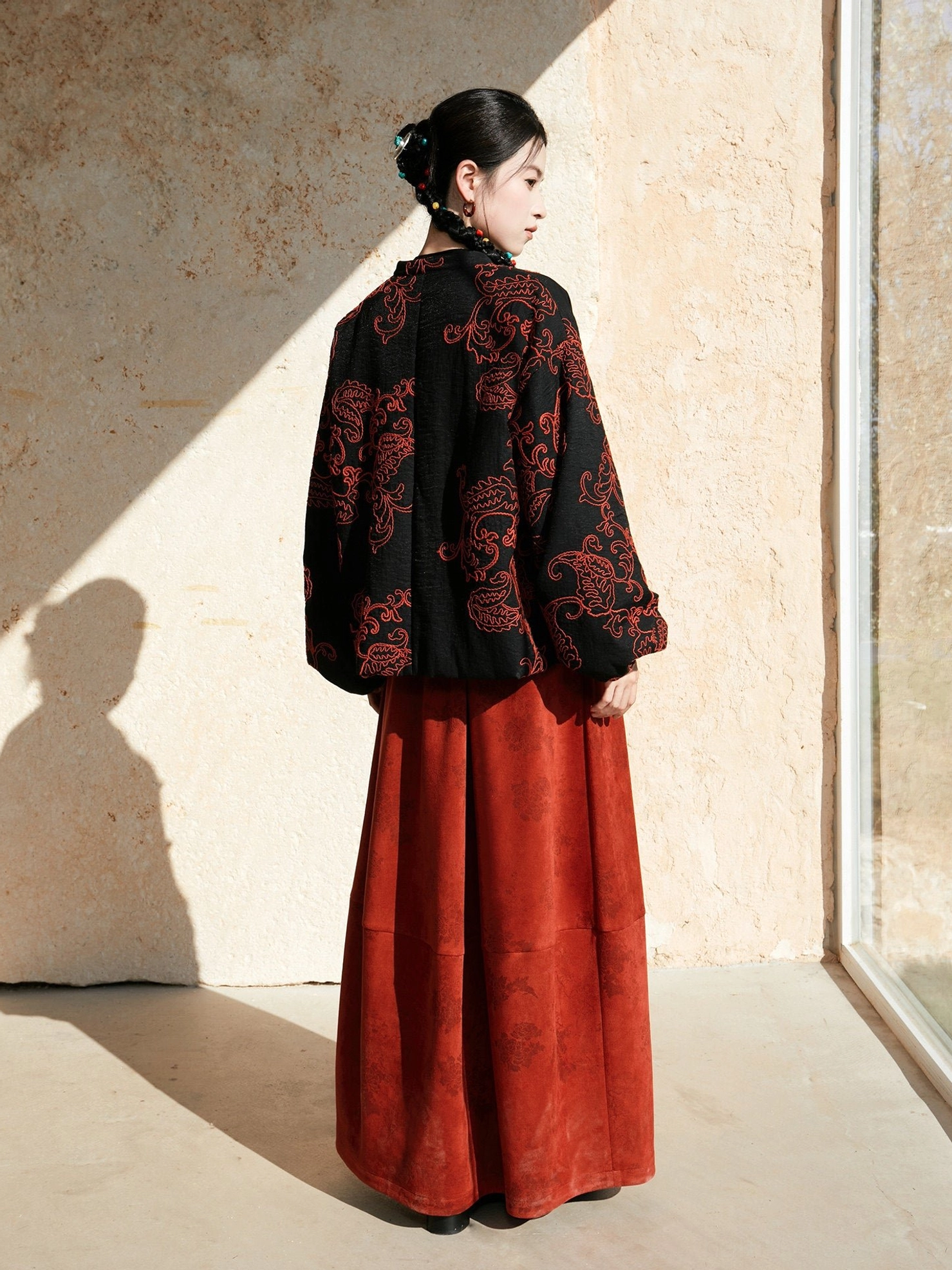 Back view of a black modern Hanfu jacket fully decorated with red paisley embroidery and flowing lantern sleeves