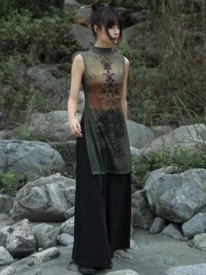 Full-length side view of a modern Hanfu sheer mesh sleeveless long tunic top with olive-brown gradient fabric, Tang-inspired floral totem prints, high stand collar, and side split hem worn outdoors by a riverside