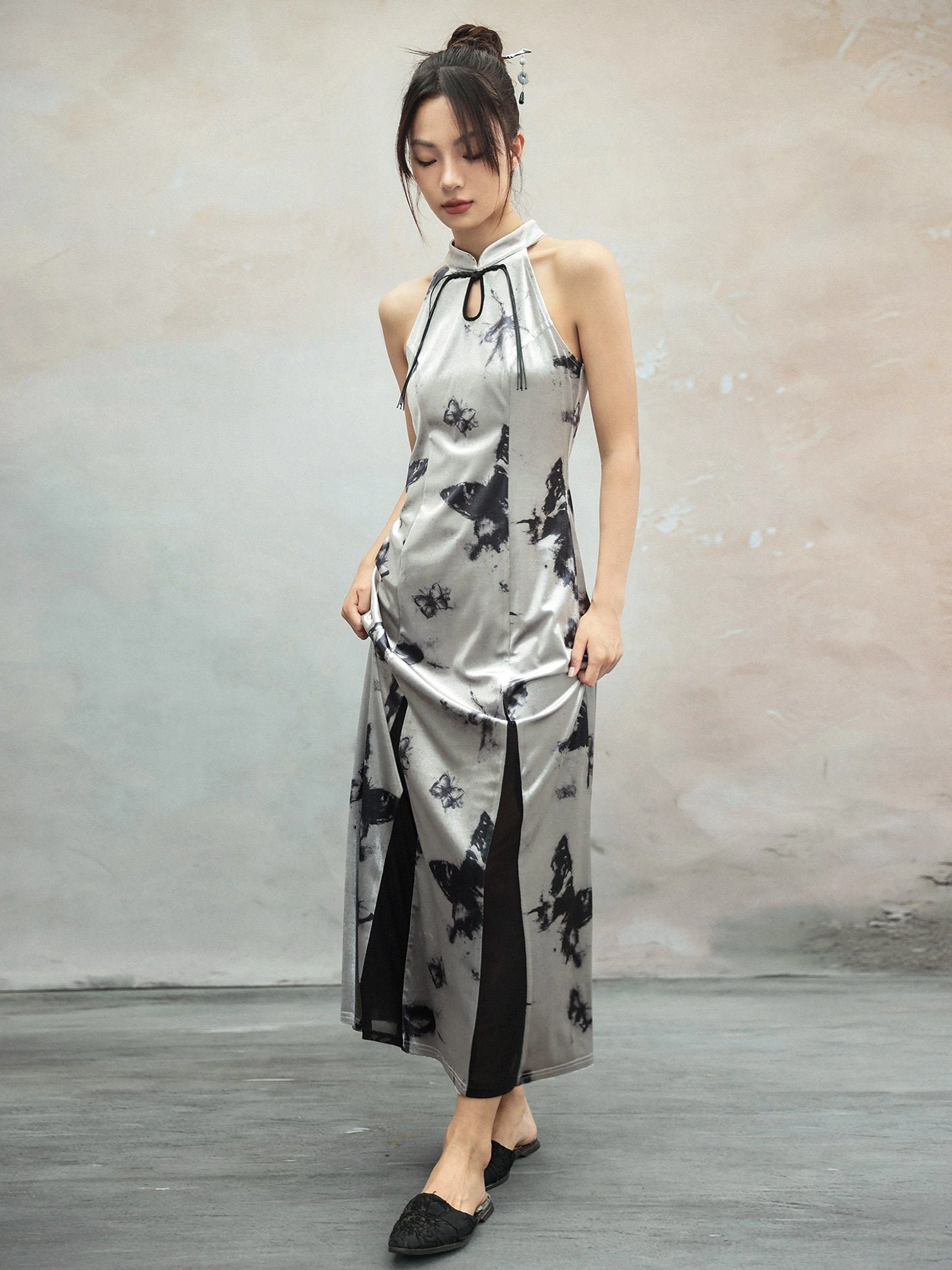Full three-quarter front view of a modern Hanfu silver butterfly print halter cheongsam dress with sleeveless stand collar, glossy fabric, high side slit, and black flat mules