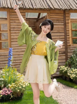 Modern Hanfu summer outfit with wide sleeve embroidered cardigan and pleated beige shorts shown in a dynamic outdoor garden jumping pose