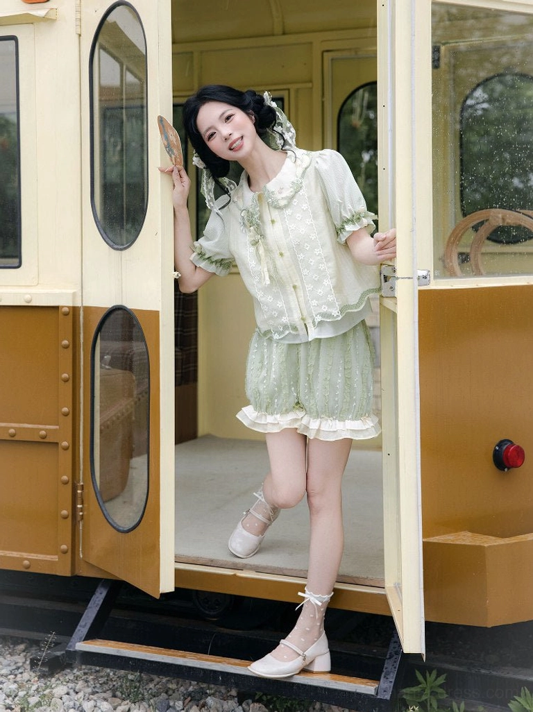 Model wearing a light green modern Hanfu summer shirt and bloomers set with doll collar, ruffled trim, and sheer puff sleeves beside a vintage tram