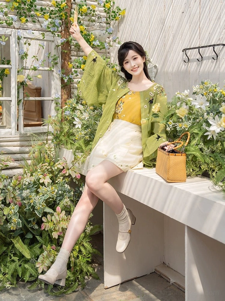 Modern Hanfu summer three piece set with embroidered cardigan and skirt style beige shorts paired with a woven rattan handbag in a garden