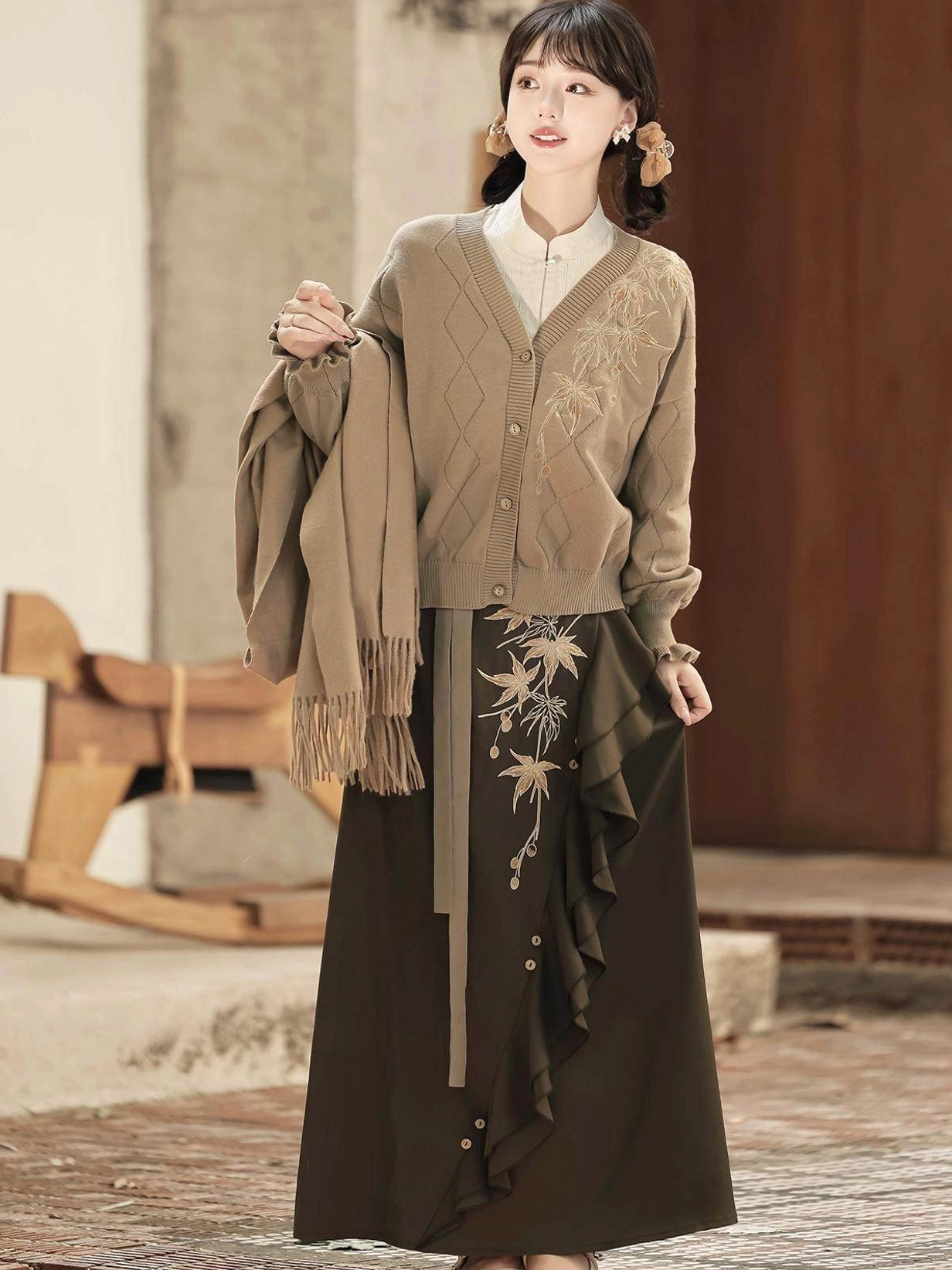 Three quarter view of a warm neutral modern Hanfu three piece outfit with knit cardigan long sleeve top and embroidered skirt