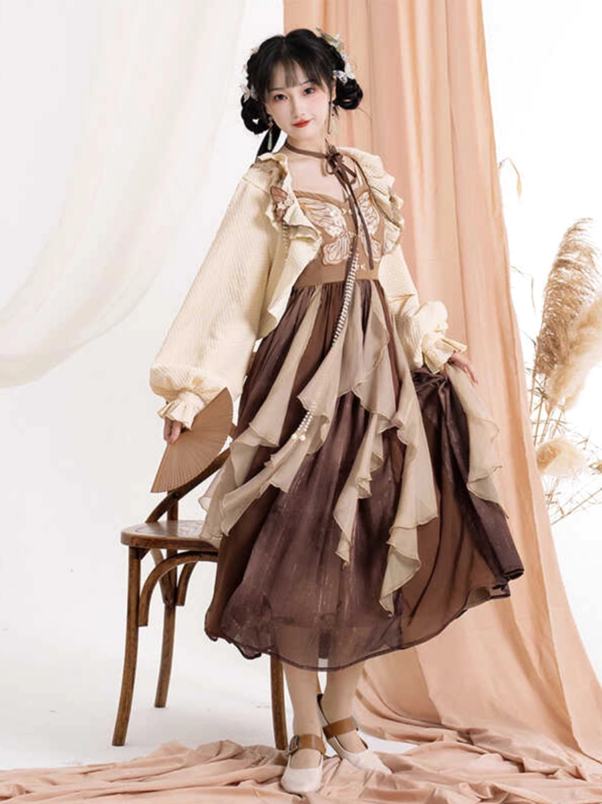 Front three-quarter view of a modern Hanfu vintage Chinese slip dress and cropped ruffled cardigan outfit in brown and cream with embroidered bust and layered midi skirt