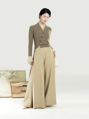 Modern Hanfu women’s taupe knit top and beige palazzo pants set shown in a full-body side view with Chinese landscape artwork in the studio background