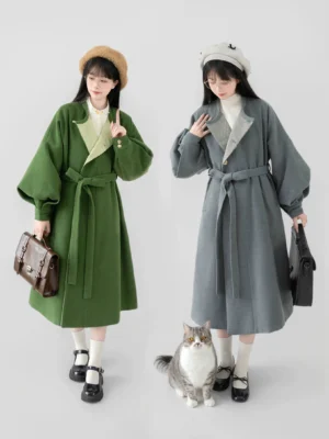 Two women wearing green and gray modern Hanfu wool-look coats with puff sleeves, matching waist belts, berets, and leather handbags in a studio setting
