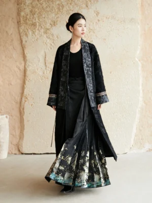 Full-body side view of a woman wearing a long black modern Hanfu woven jacquard coat with subtle dark floral pattern and landscape pleated skirt