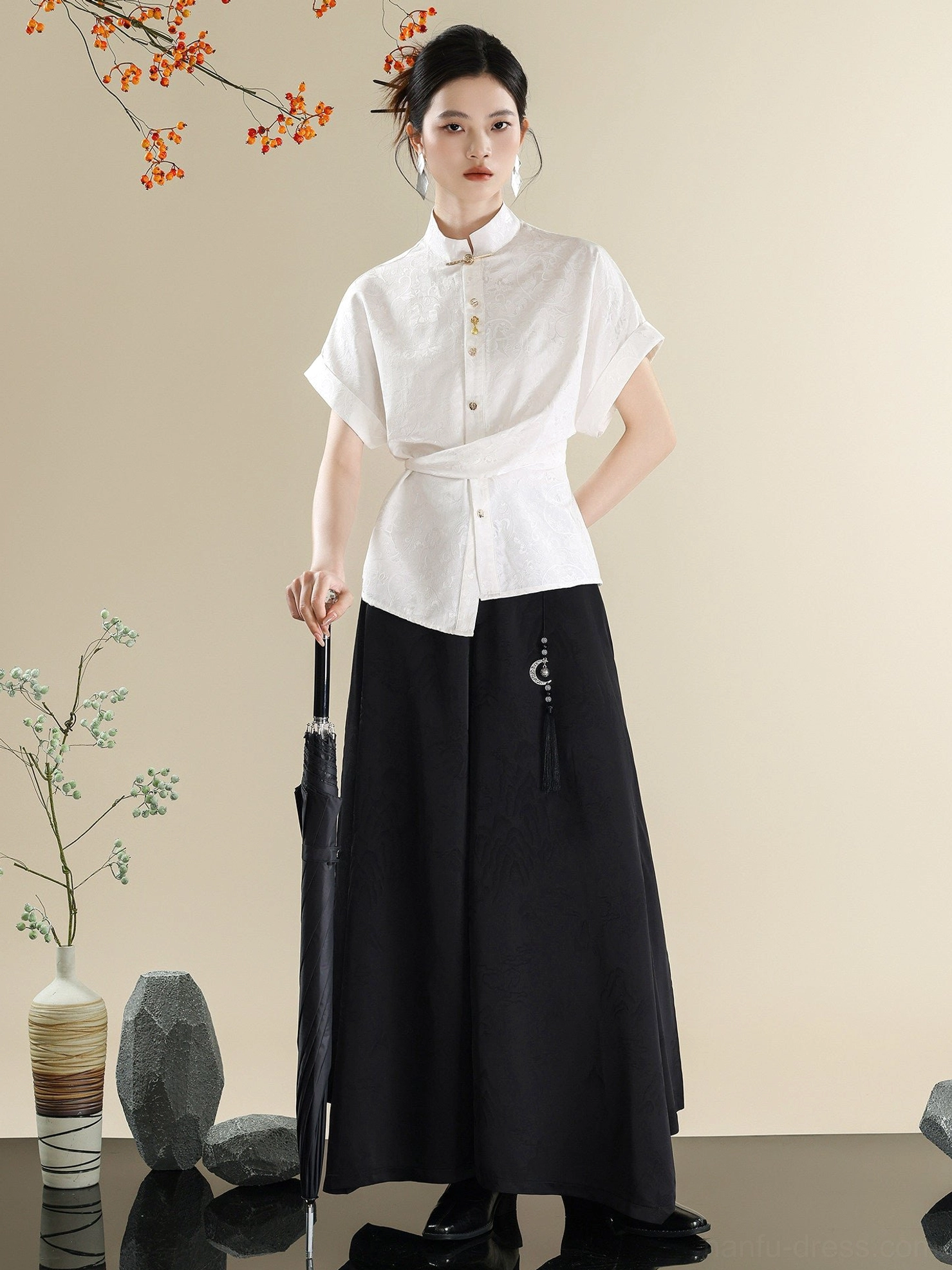 Side view of a contemporary Hanfu wrap-front white shirt styled without the waist sash with black flowing wide-leg trousers and tassel pendant
