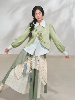 Three-quarter view of a modern Hanfu xianxia outfit with asymmetrical curved jacket hem, crochet waist details, tassel accents, and layered patchwork skirt