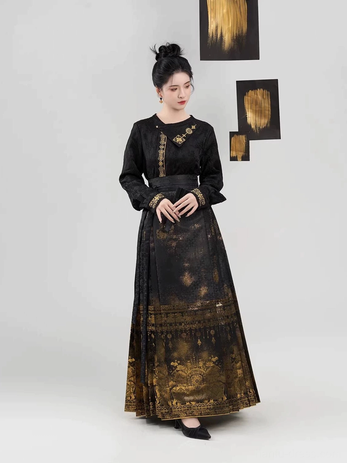 Three-quarter front view of modern Ming Dynasty Hanfu mamianqun outfit with black cropped long-sleeve top and gold gradient traditional pattern skirt