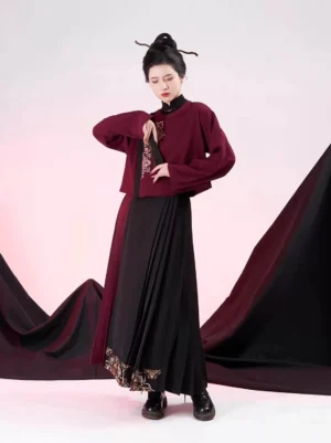 Front view of a woman wearing a modern Ming Dynasty hanfu outfit with dark red floral embroidered stand-collar jacket and black pleated mamianqun culottes