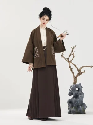 Full-body front view of a modern Ming Dynasty Hanfu outfit with dark mocha wide-sleeved embroidered jacket, ivory stand-collar inner layer, and floor-length pleated mamianqun skirt
