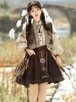 Modern Ming Dynasty Hanfu mamianqun set with embroidered brown vest, beige lantern sleeve shirt, dark horse-face skirt, tassel pendants, and feather hair accessories by a waterside stone bridge