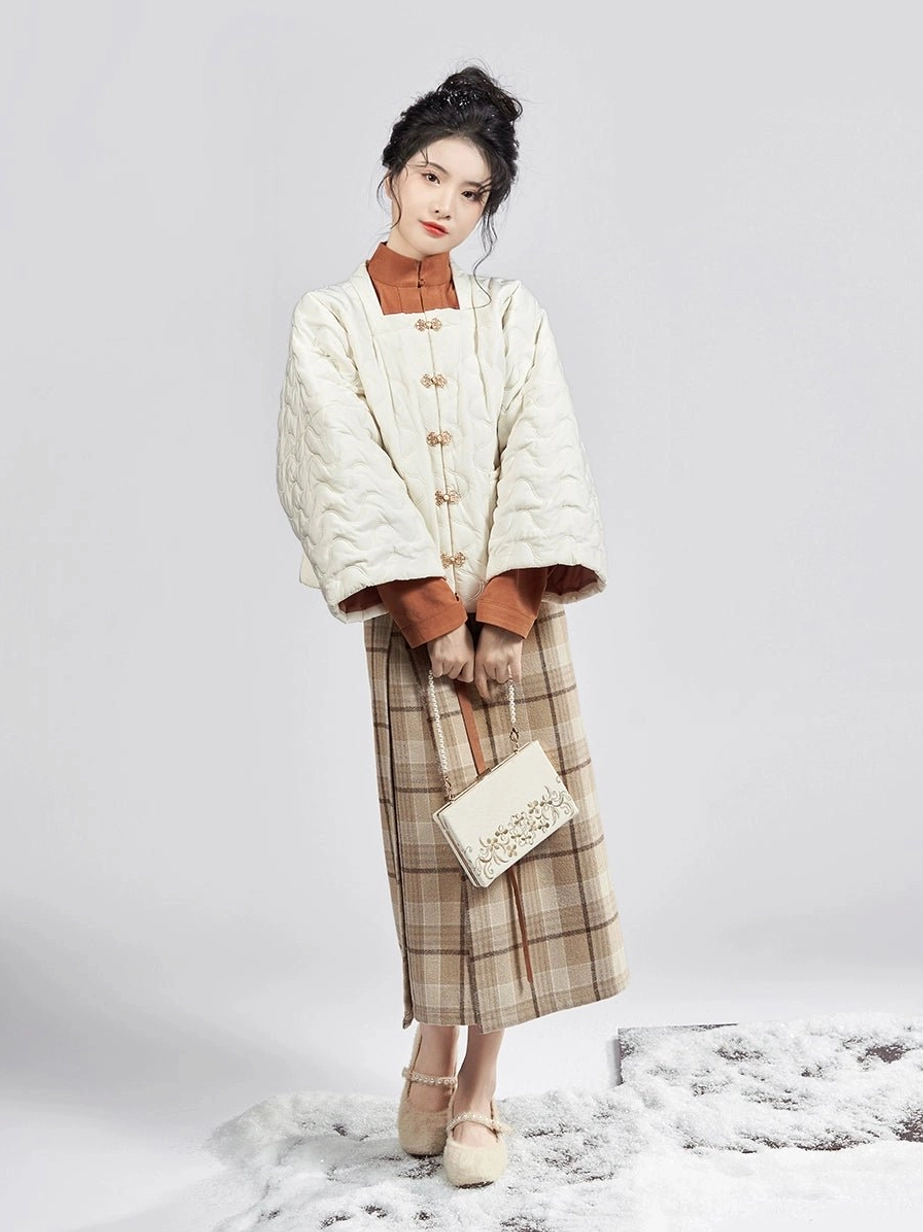 Full-body front view of a modern Ming Dynasty Hanfu three-piece outfit with cream quilted jacket caramel winged-sleeve top and beige plaid mamianqun wrap skirt