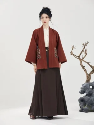 Full-body front view of a modern Ming Dynasty Hanfu outfit with rust red wide-sleeved jacket, floral embroidery details, and dark brown pleated mamianqun skirt