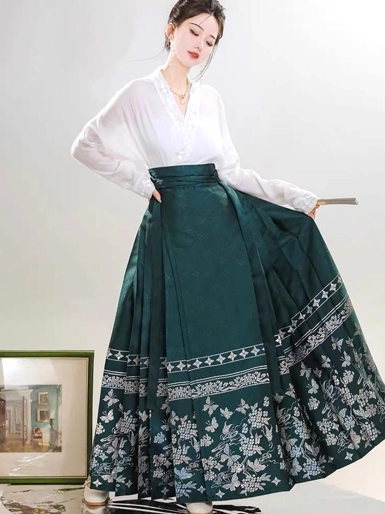 Modern Ming Dynasty Hanfu set with white cross-collar top and dark green embroidered mamianqun horse face skirt shown in a three-quarter full-body studio view