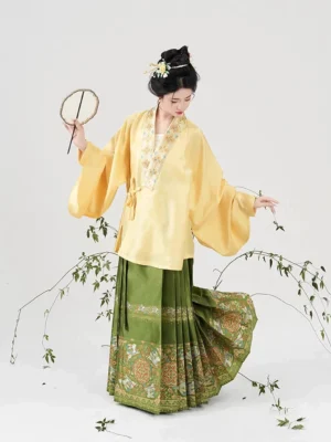 Full-body side view of modern Ming Dynasty Hanfu yellow cross-collar top and pleated green mamianqun skirt with decorative patterned hem