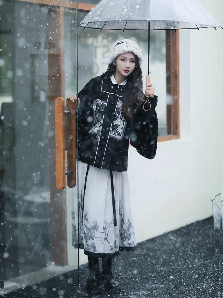 Half-body view of a modern Chinese hanfu outfit featuring a black padded jacket, white piping, stand collar, and ink-wash mamianqun skirt by a rainy shop entrance