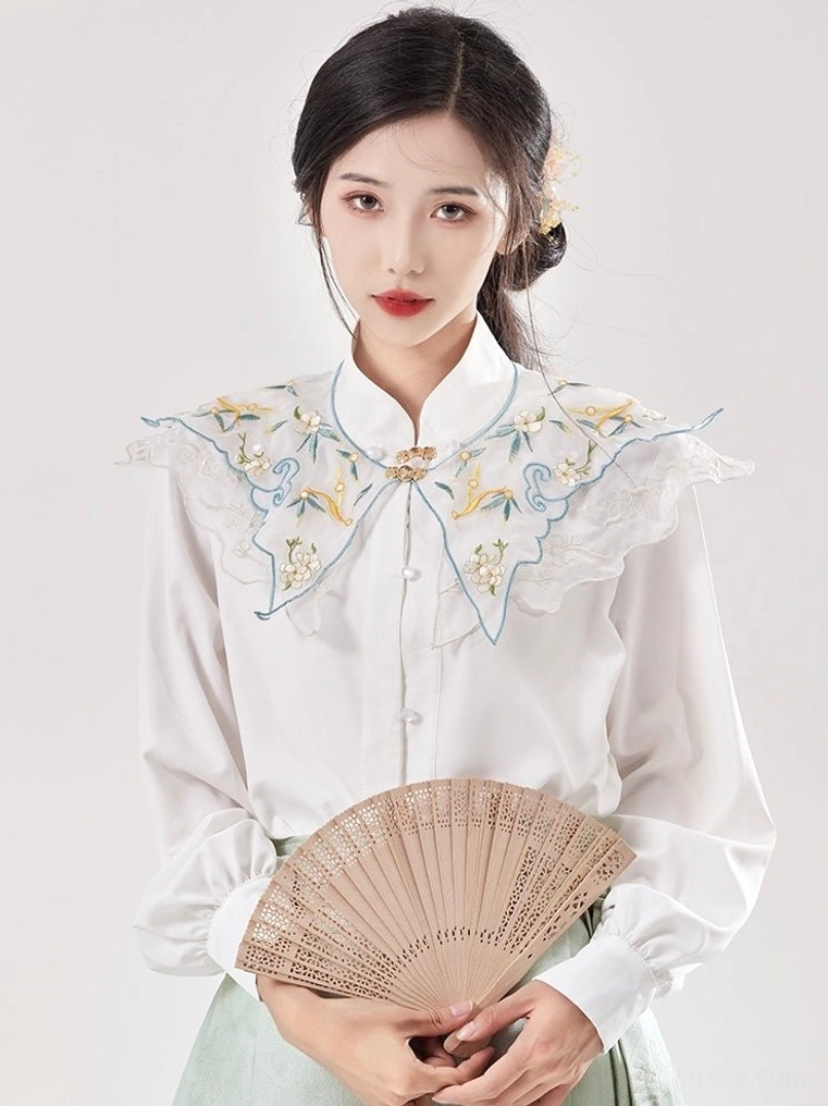 Close-up of blue and yellow floral embroidered cloud collar on white modern Ming Dynasty Hanfu blouse with light green mamianqun