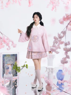 Modern Ming style Hanfu set with pastel pink floral cross collar top and pleated mamianqun horse face skirt worn in a cherry blossom studio