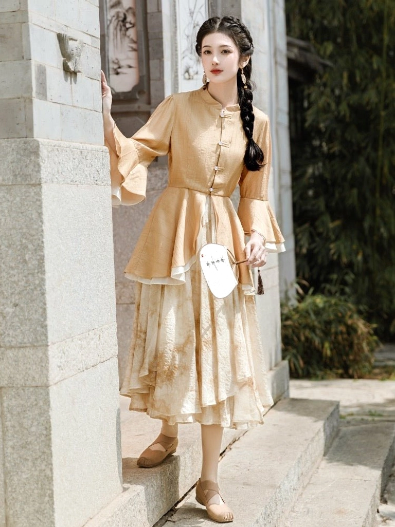 Front three-quarter view of a modern Ming inspired Hanfu set with peplum stand collar top, ruffle sleeves, gradient skirt, and Chinese round fan