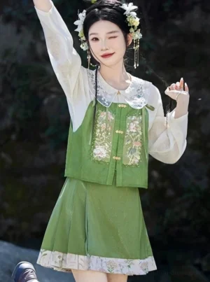 Modern Chinese Hanfu fashion model wearing a sage-green embroidered bustier and pleated floral skirt with ivory blouse in a woodland setting