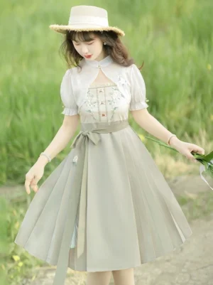 Modern Ming style Hanfu dress in sage green with floral embroidered bodice sheer puff sleeves pleated skirt and waist bow worn outdoors