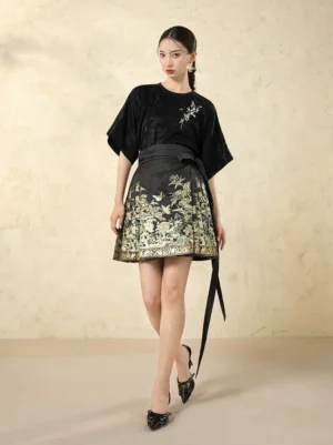 Front view of a modern Ming style Hanfu mini mamianqun horse-face skirt set with black floral jacquard top, green and gold landscape print skirt, and black pointed heels