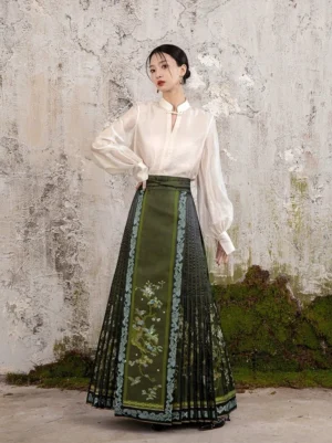 Front three-quarter view of a dark olive green modern Ming style mamian skirt with pleats, floral decoration, light blue trim, and high waist Hanfu design