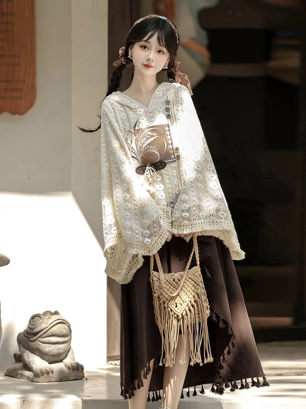 Side view of modern New Chinese style Hanfu clothing featuring a hollow floral lace hooded top with crocheted sleeve trim and matching brown tassel hem skirt