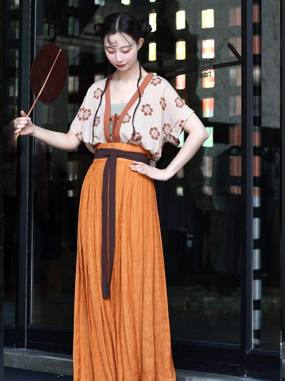 Modern Qiyao Ruqun hanfu styling with floral vest, orange skirt, brown sash, and round silk fan