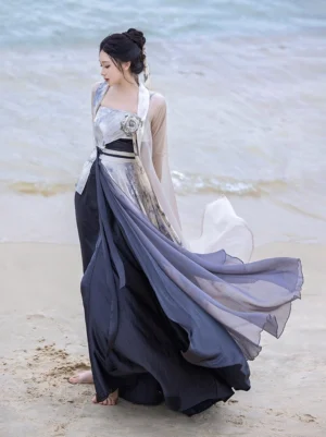 Modern Song Dynasty Hanfu full set with ink wash camisole, sheer off-white beizi jacket, flowing sash belt, and dark grey gradient wrap skirt styled on a seaside beach