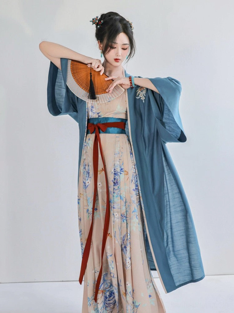 Modern Song Dynasty Hanfu outfit styled with a folding fan, dusty blue Beizi outer jacket, printed apricot slip dress, traditional hair ornaments, and elegant vintage accessories