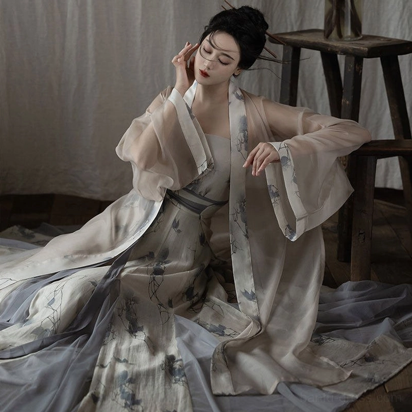Seated model wearing modern Song Dynasty Hanfu full set with ivory jacket blue floral camisole and pleated skirt