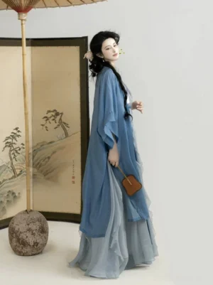 Modern Song Dynasty style Hanfu dress set shown from a right three-quarter view with flowing blue layers and a small brown leather handbag