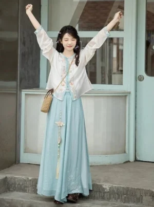 Full-body front view of a modern Song Dynasty hanfu set in Pure Jade jasper green with floral embroidered round-neck top, flowing blue lower garment, tassel charm, and crossbody bag