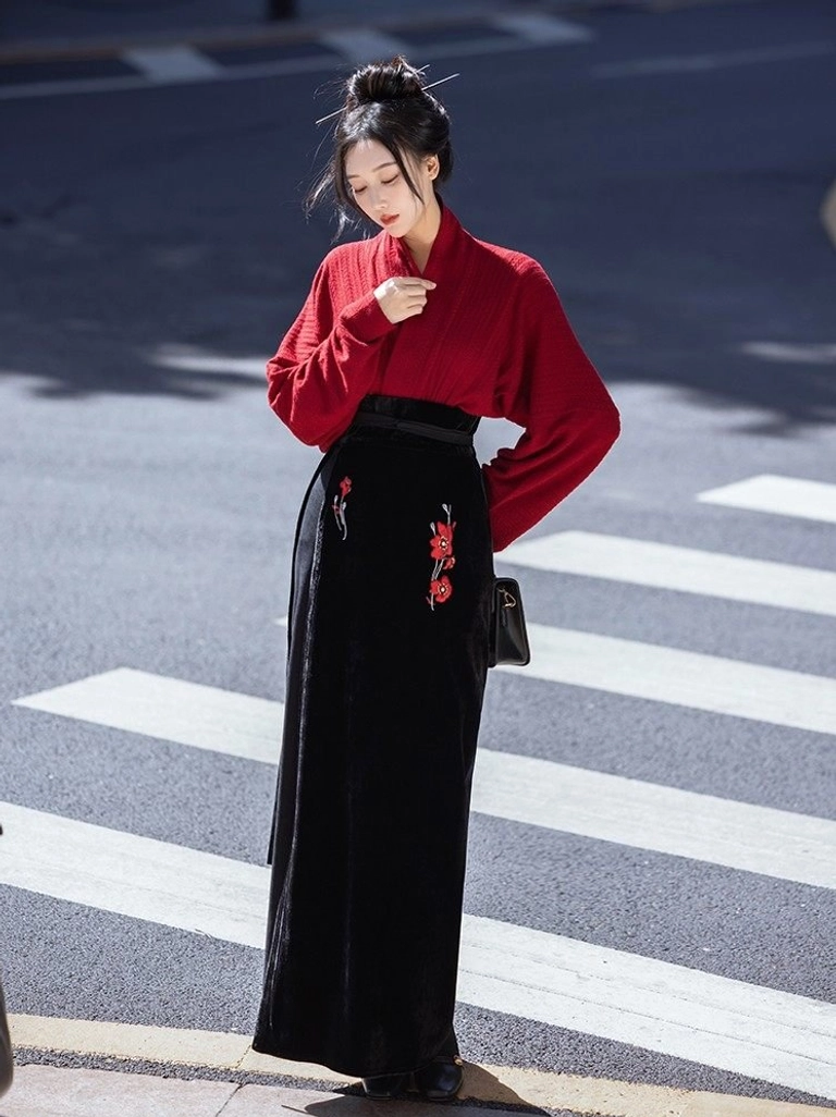 Modern Song Dynasty Hanfu two piece outfit with deep red wing sleeve cross collar top and black embroidered wrap skirt modeled outdoors