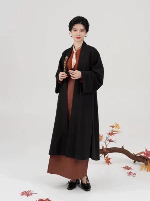 Front view of a modern Song Dynasty hanfu set featuring a flowing black outer jacket, rust-red cross-collar top, and coordinated wrap skirt