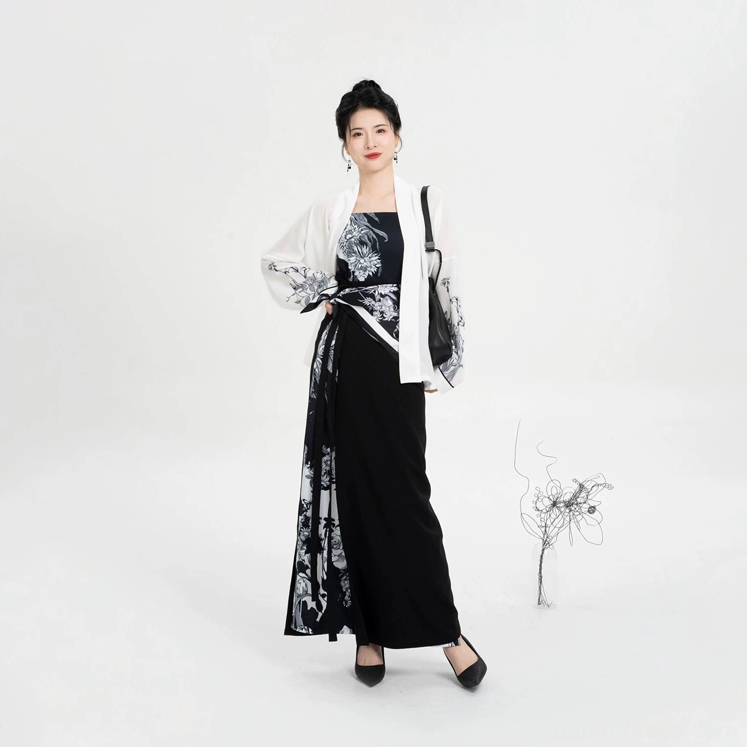 Three-quarter side view of modern Song Dynasty Hanfu three-piece outfit with draped wrap skirt, winged sleeves, and matching black handbag