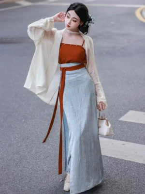 Full body front view of a woman wearing a modern Song Dynasty Hanfu three piece set with cream winged sleeve top terracotta camisole and light blue wrap skirt