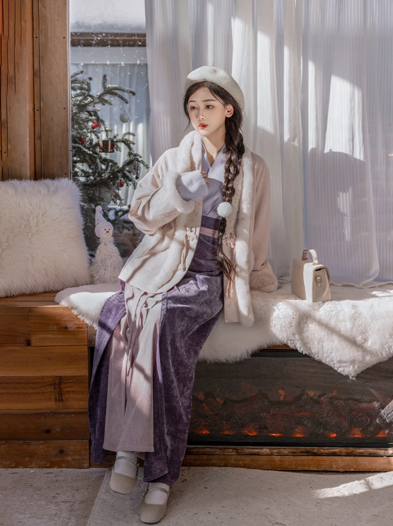 Modern Song Dynasty hanfu winter outfit with faux fur trimmed coat and dark purple wrap skirt worn by a seated woman in a cozy indoor studio