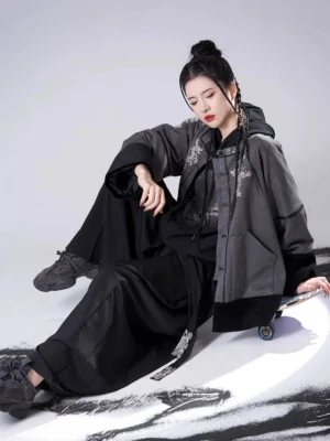 Seated side view of a contemporary Song Dynasty Hanfu outfit with an unbuttoned jacket, black hooded sweater, wide-leg pants, and tassel waistband detail