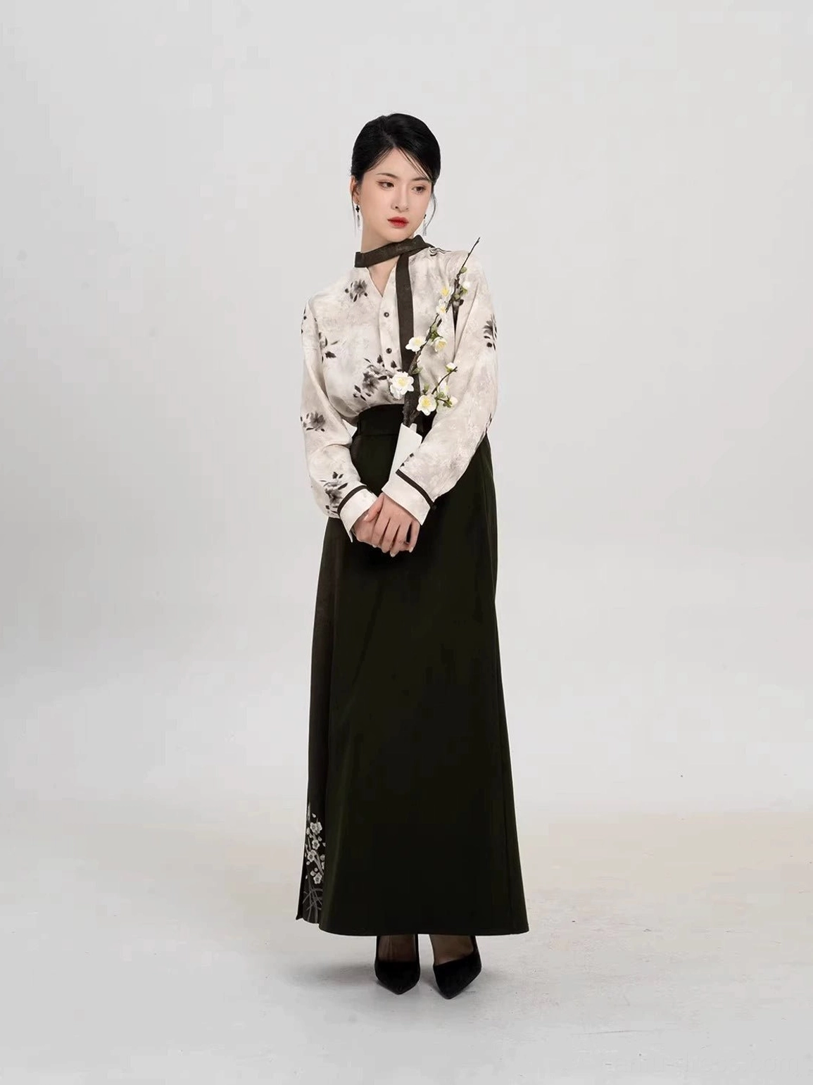 Front view of modern Song-style Hanfu outfit with ink plum top and dark green skirt featuring floral embroidery at the hem