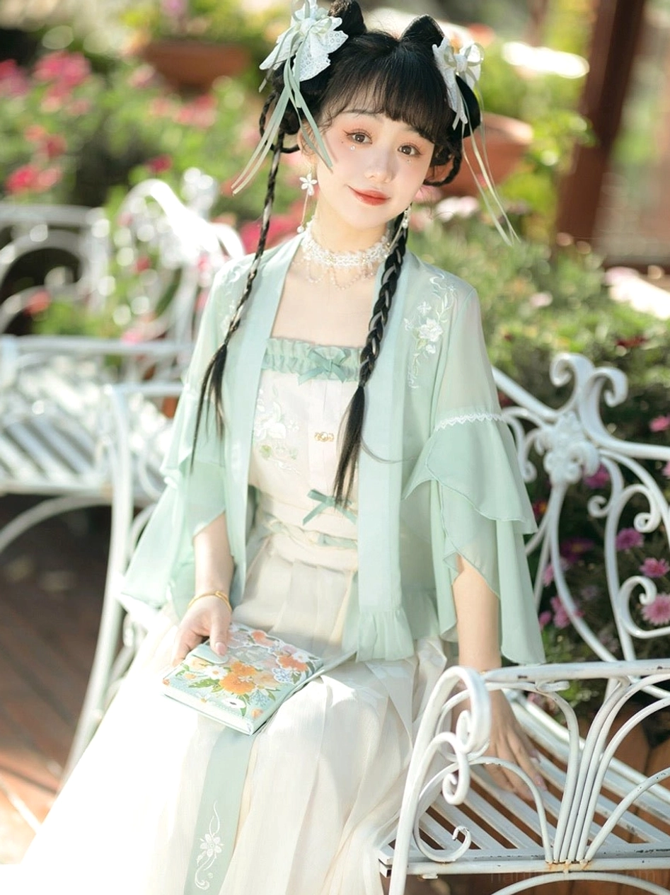 Modern Song style Hanfu three-piece outfit in a flower garden with floral accessories pearl choker painted hand fan and soft golden hour light