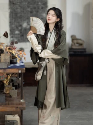 Modern Song style Hanfu outfit with olive green calligraphy cardigan and folding fan three-quarter view