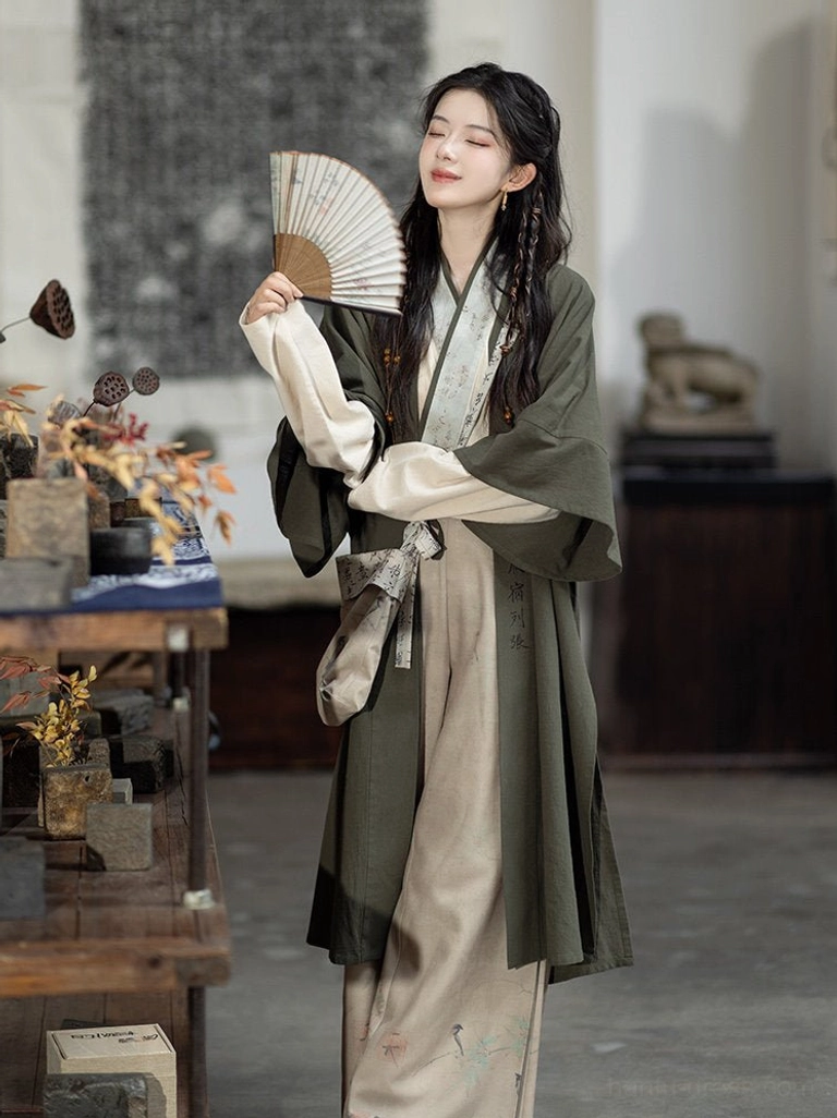 Modern Song style Hanfu outfit with olive green calligraphy cardigan and folding fan three-quarter view