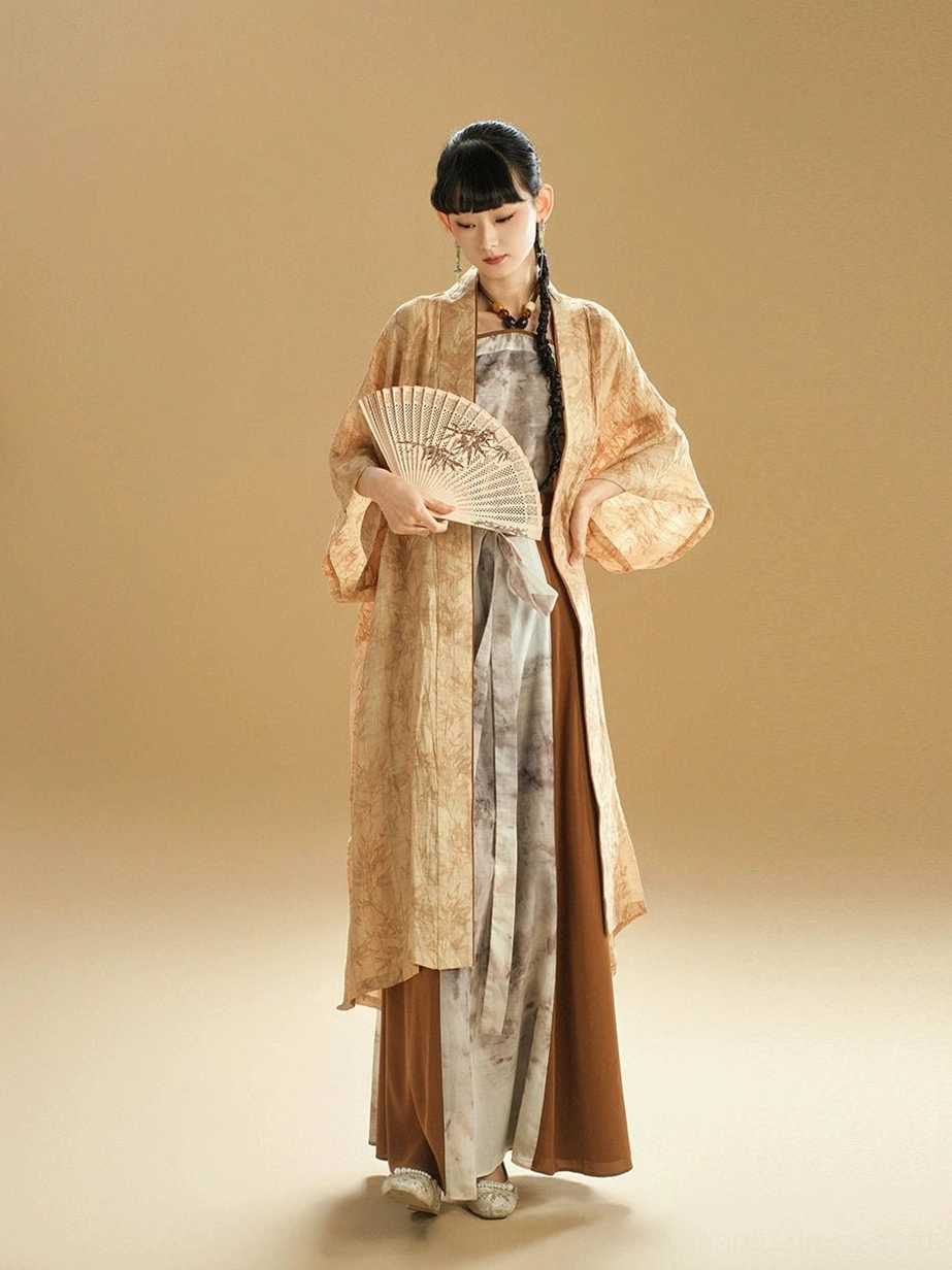 Three-quarter view of a modern summer Hanfu outfit with an earthy ink-wash cardigan, brown waist sash, loose sleeves, and folding fan styling
