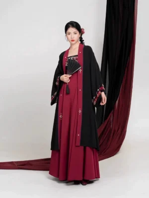 Modern Tang Dynasty Hanfu outfit in black and burgundy with embroidered slip dress, dark red jacket trim, decorative front details, and traditional Chinese folding fan