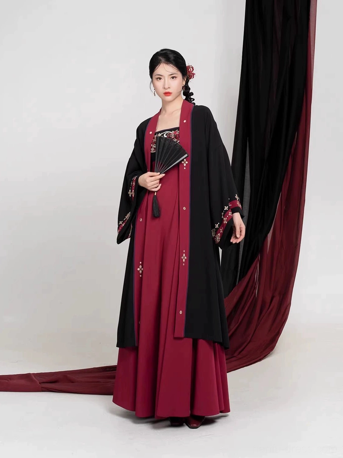 Modern Tang Dynasty Hanfu outfit in black and burgundy with embroidered slip dress, dark red jacket trim, decorative front details, and traditional Chinese folding fan