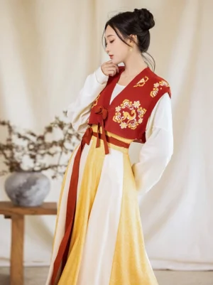 Side three-quarter view of a modern Tang Dynasty Hanfu ensemble showing embroidered beizi vest details, tied waist sash, and layered color-block twelve-panel wrap skirt